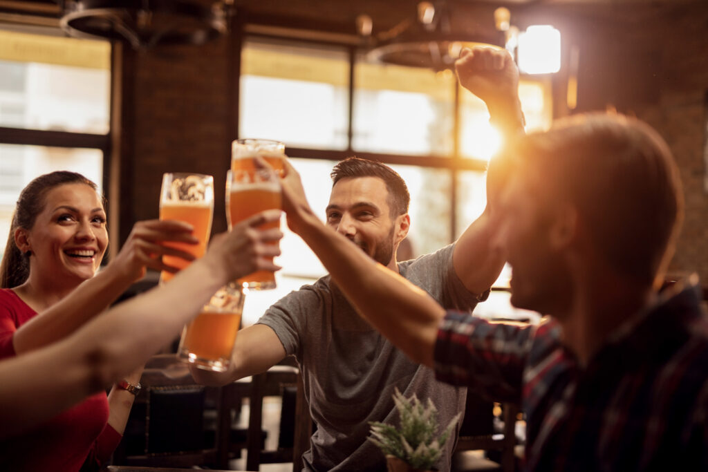 group of cheerful friends toasting with beer in a bar.